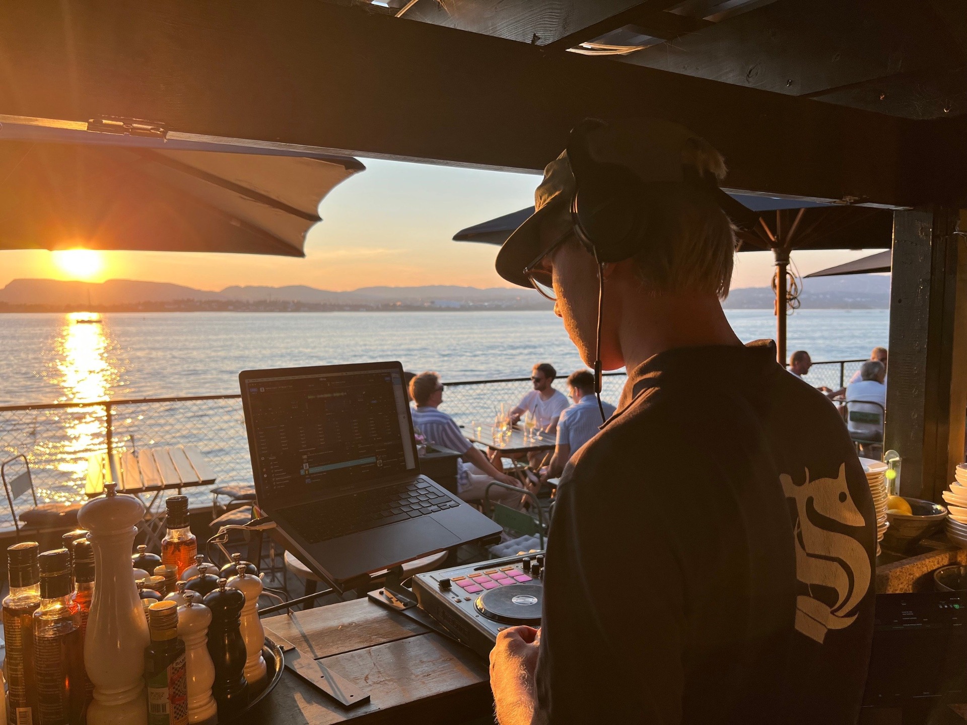 Langbord dekket til selskap på terrassen, med utsikt over fjorden i solnedgang